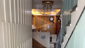 A hotel reception area with a marble floor, a reception desk, a clock, and a staircase. - Hotel Rajshree (Hisar)