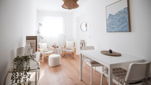 A modern, well-lit room with a dining table, chairs, a hanging light fixture, and a wall-mounted painting. - Luxury Apartment on the Edge of the Forest, Close to the City (Bornheim)