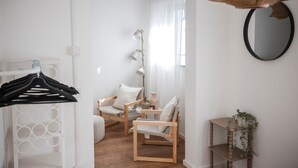 A room with a wooden chair, a small table, a hanging lamp, and a mirror on the wall. - Luxury Apartment on the Edge of the Forest, Close to the City (Bornheim)
