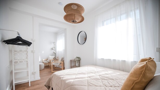 A bedroom with a bed, a hanging light fixture, a mirror, and a window with curtains. - Luxury Apartment on the Edge of the Forest, Close to the City (Bornheim)