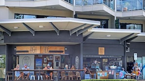 An outdoor seating area of a restaurant with a modern design, featuring a sign that reads "HIGH TIDE."