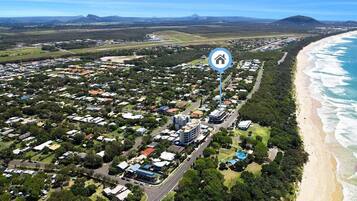 An aerial view of a coastal town with residential areas, a beach, and a prominent hotel icon indicating a hotel presence.