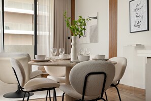 Un espace repas moderne avec une table ronde, des chaises blanches et un vase contenant des plantes vertes.