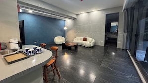 Uma sala de estar moderna com um balcão curvo, área de estar e uma janela grande.