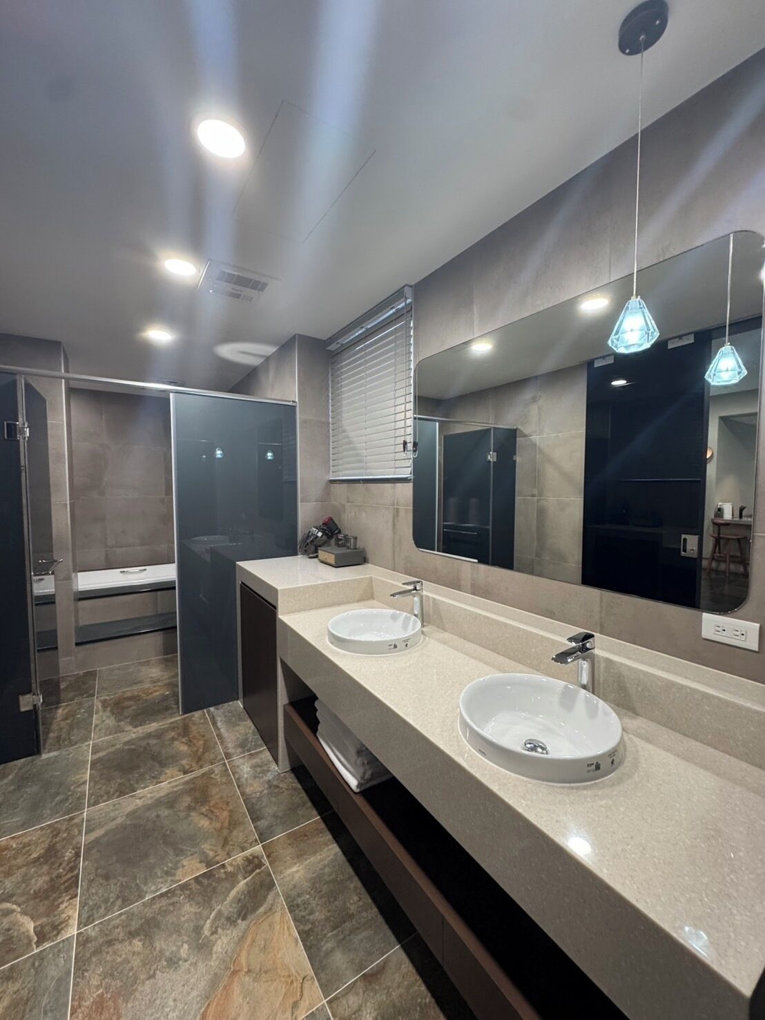 A modern bathroom with two sinks, a large mirror, and a shower area.