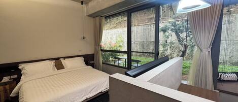 A bedroom with a bed, a window with curtains, and a view of the outdoors.