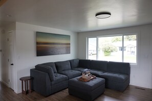 A modern living room with a sectional sofa, a small side table, and a large window with a view of the outside.