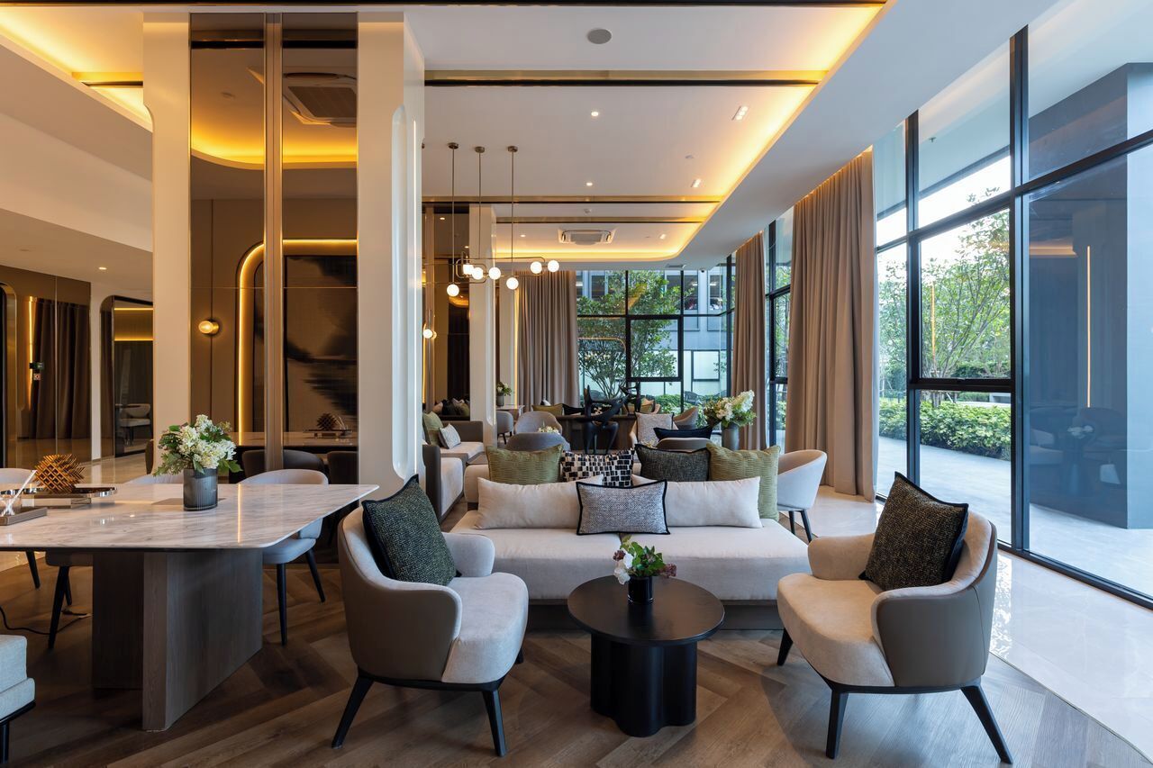 A modern hotel lobby with a central seating area, a dining space, and large windows offering views.