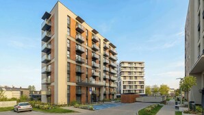 En modern lägenhetsbyggnad med flera balkonger, en parkeringsplats och en välskött trädgård.