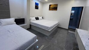 Una habitación de hotel moderna con dos camas, ventilador de techo, iluminación empotrada y obras de arte en las paredes.