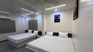Una habitación de hotel moderna con dos camas individuales, un ventilador de techo, iluminación empotrada y un cuadro en la pared.
