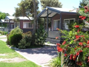 A row of mobile homes with a covered porch, surrounded by well-maintained lawns and flowering plants. - BIG4 Robe Lakeside Tourist Park (Robe)