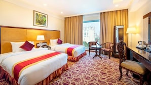 A hotel room with two beds, a desk, a chair, and a large window with curtains. - Chayabithi beach resort (Cox's Bazar)