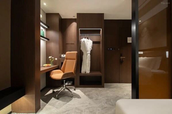 A modern hotel room with a wooden wardrobe, a seating area with a chair, and a small table with a vase of flowers. - Giorgio Morandi Hotel (Nanjing Yueyahu & NUAA) (Nanjing)