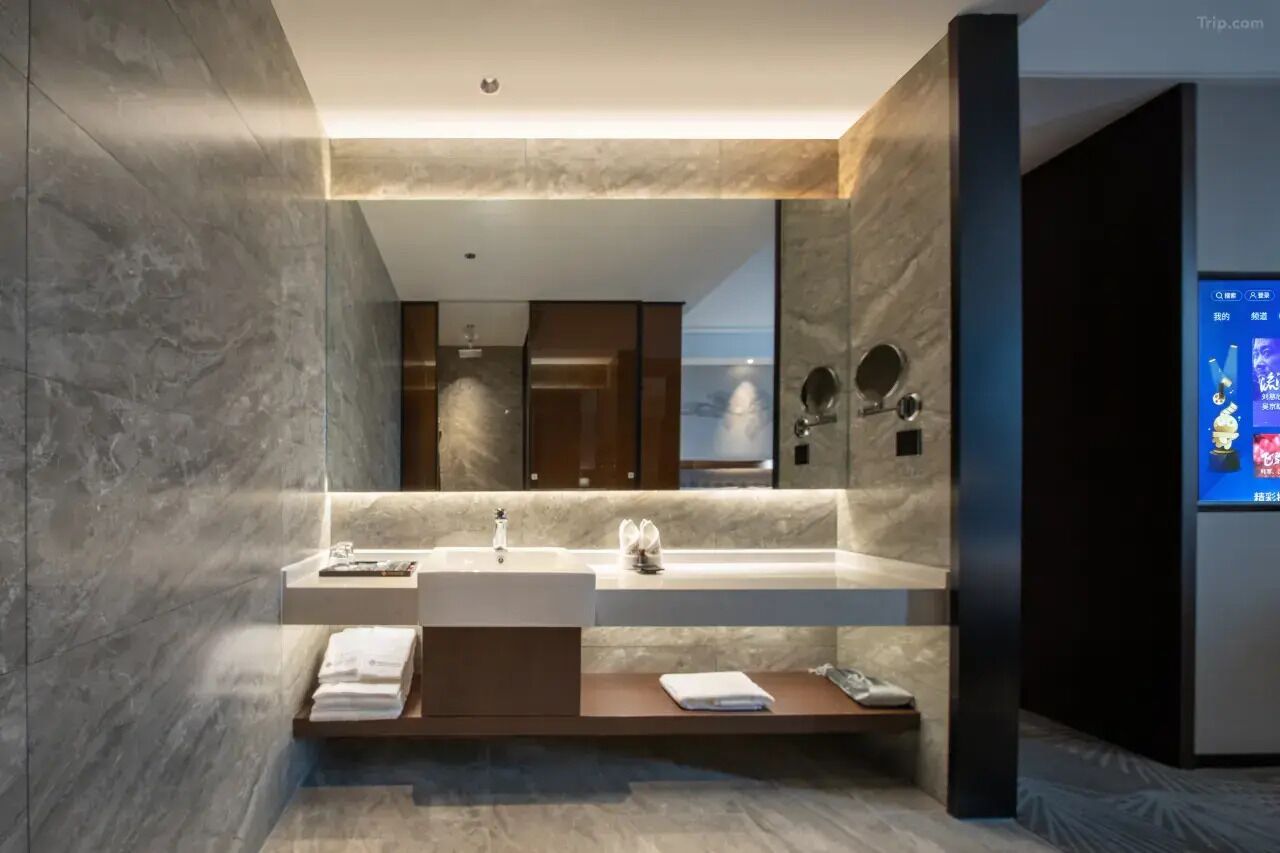 Un baño moderno con un espejo grande, dos lavamanos y un mueble de tocador con un perchero para toallas.