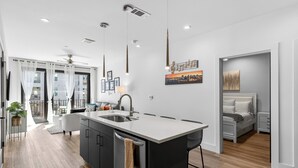 Une cuisine moderne dotée d’un îlot central, d’un coin repas et d’une chambre à coucher comprenant un lit et une table de chevet.