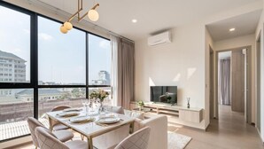 Una sala de estar moderna con comedor, ventanas amplias y un televisor de pantalla plana.
