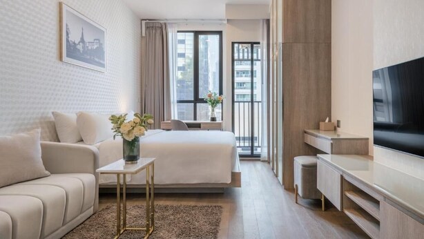 Una habitación de hotel moderna con cama, sofá, televisor y escritorio.