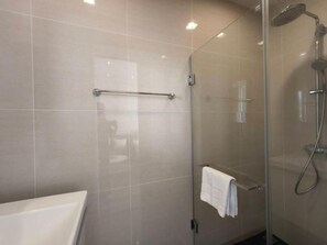 Een moderne badkamer met een glazen douchecabine, een handdoekhouder en een zichtbaar toilet.