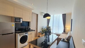 Una cocina moderna con microondas, horno y lavadora. Hay una mesa de comedor con sillas y un sofá en la sala de estar.