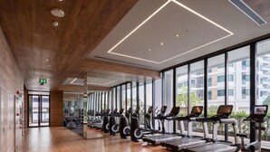 Un gimnasio moderno con cintas de correr y bicicletas estáticas, ventanas amplias y techo de madera.