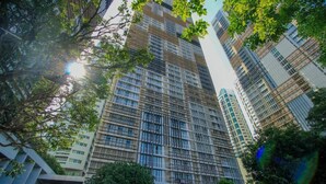 Un edificio de gran altura con fachada de diseño geométrico, rodeado de árboles y otros edificios.