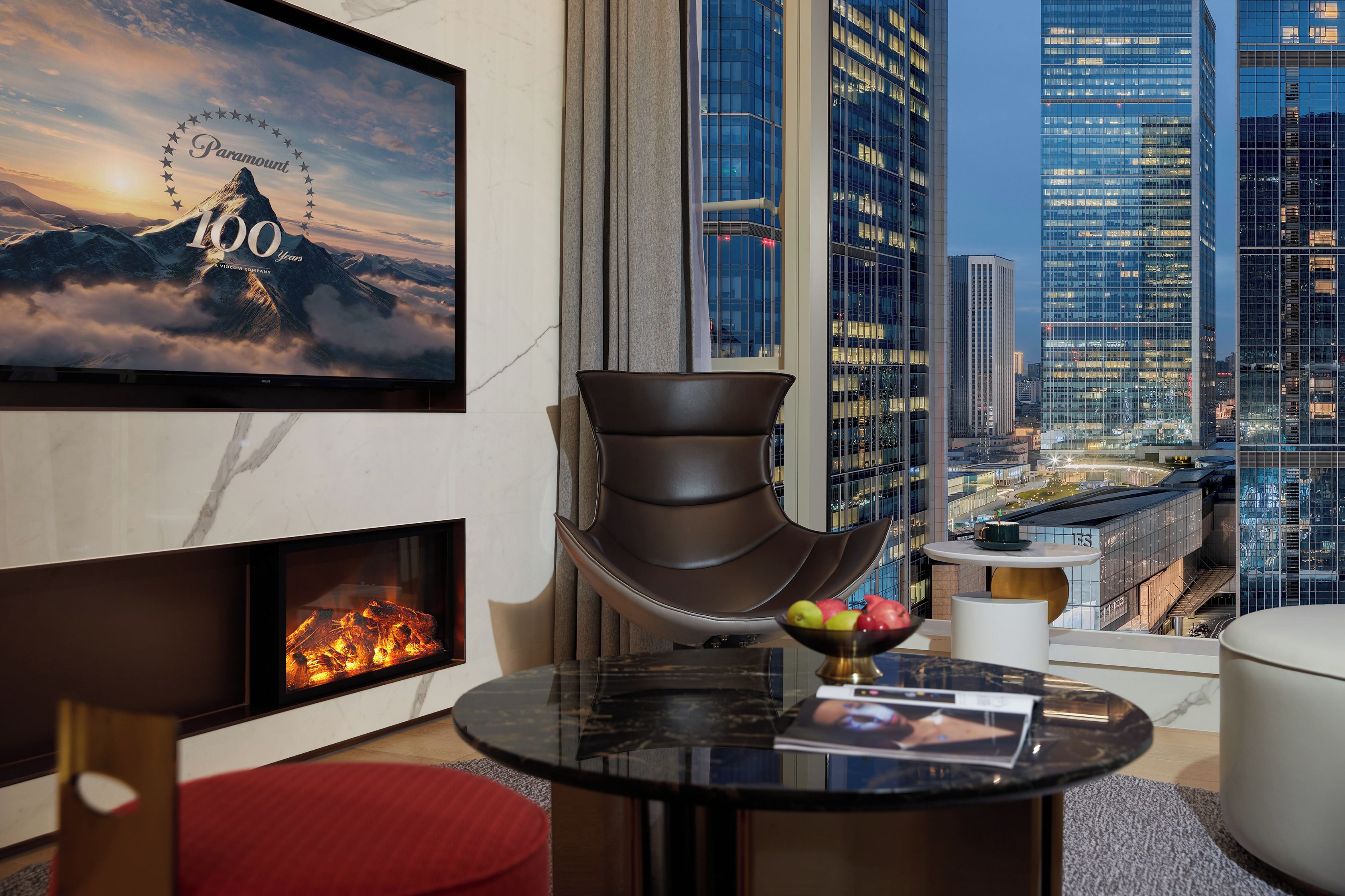 Una sala de estar moderna con chimenea, televisor de pantalla plana y vista a la ciudad.