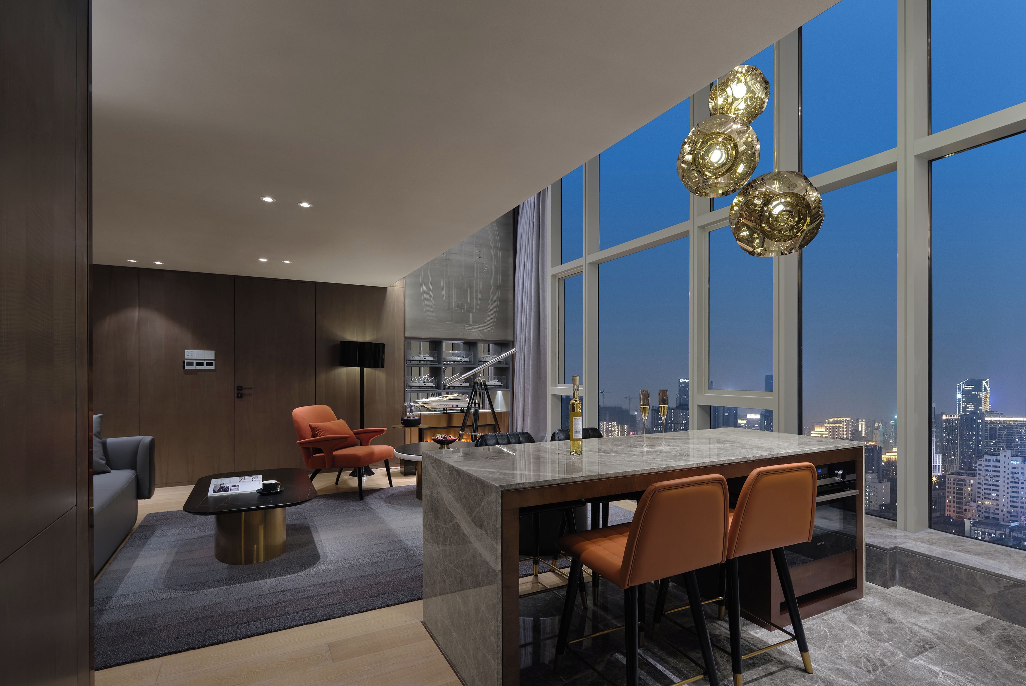 Una cocina moderna con isla de mármol, comedor y ventanas grandes con vistas a la ciudad.