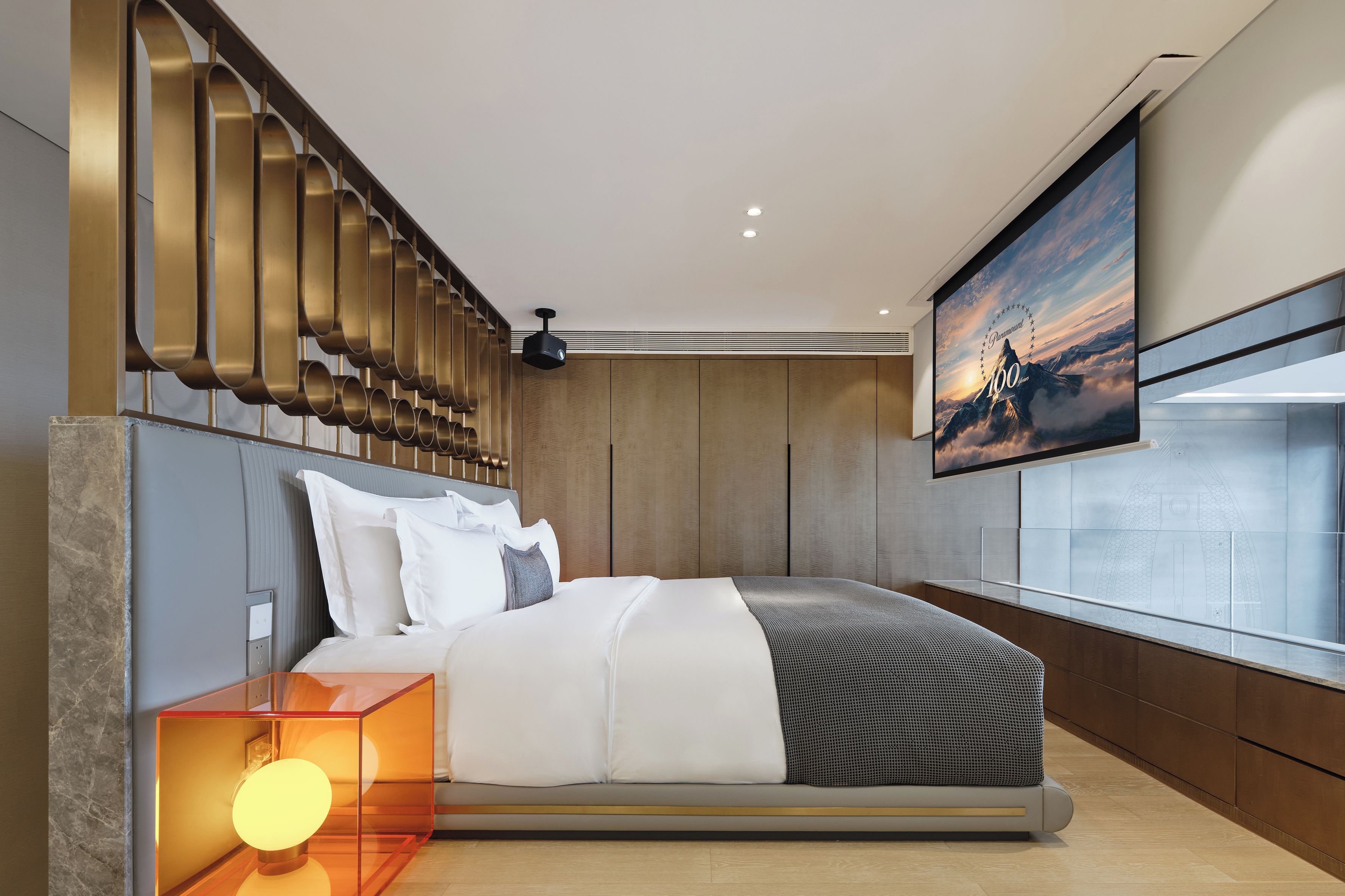 A modern bedroom with a large bed, a TV mounted on the wall, and a unique wall design.