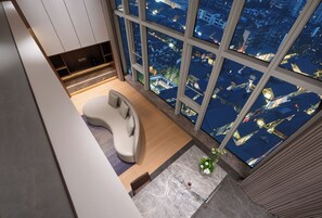 A modern living room with a curved sofa, a small table, and a large window offering a city view.