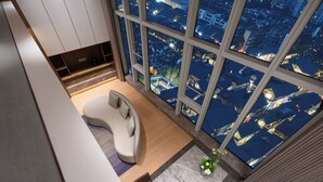 Ein modernes Wohnzimmer mit einer gebogenen Couch, einem kleinen Tisch und einem großen Fenster mit Blick auf die Stadt.