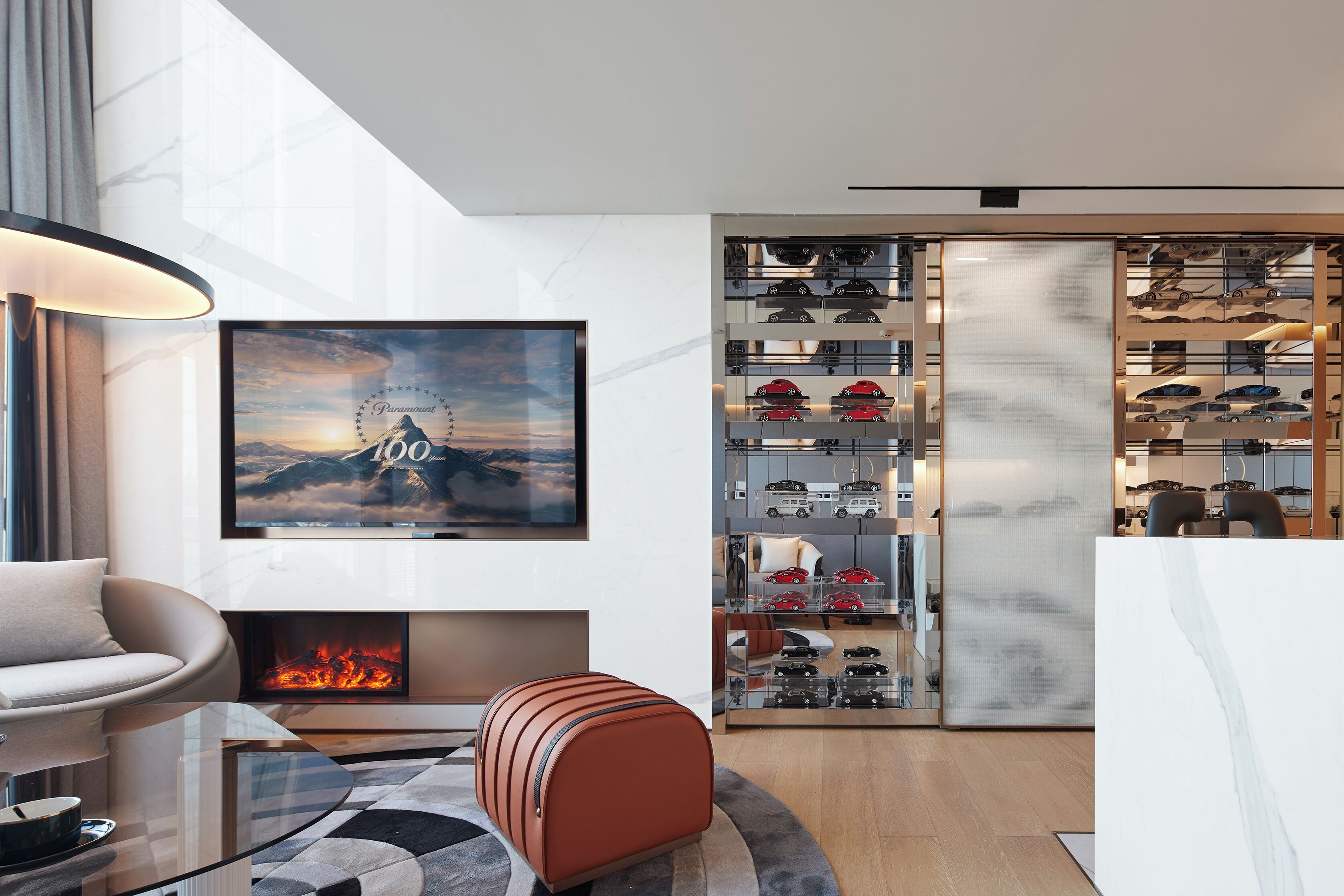 Un salon moderne doté d’une cheminée, d’un téléviseur fixé au mur et d’un meuble pour exposer les chaussures.