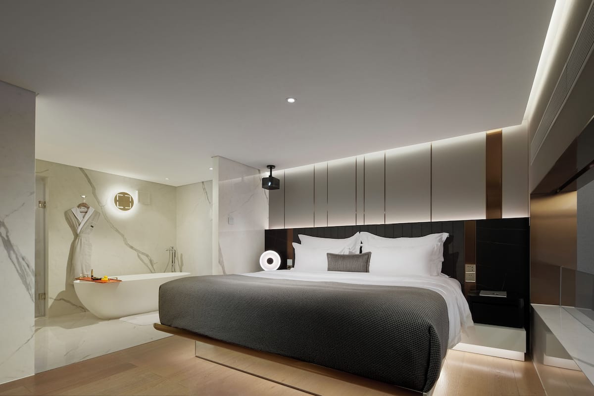 Una camera da letto moderna con un letto grande, una vasca idromassaggio integrata e un design minimalista.