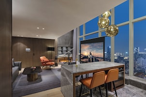 Una sala moderna con un televisor grande, una chimenea y vistas a la ciudad.