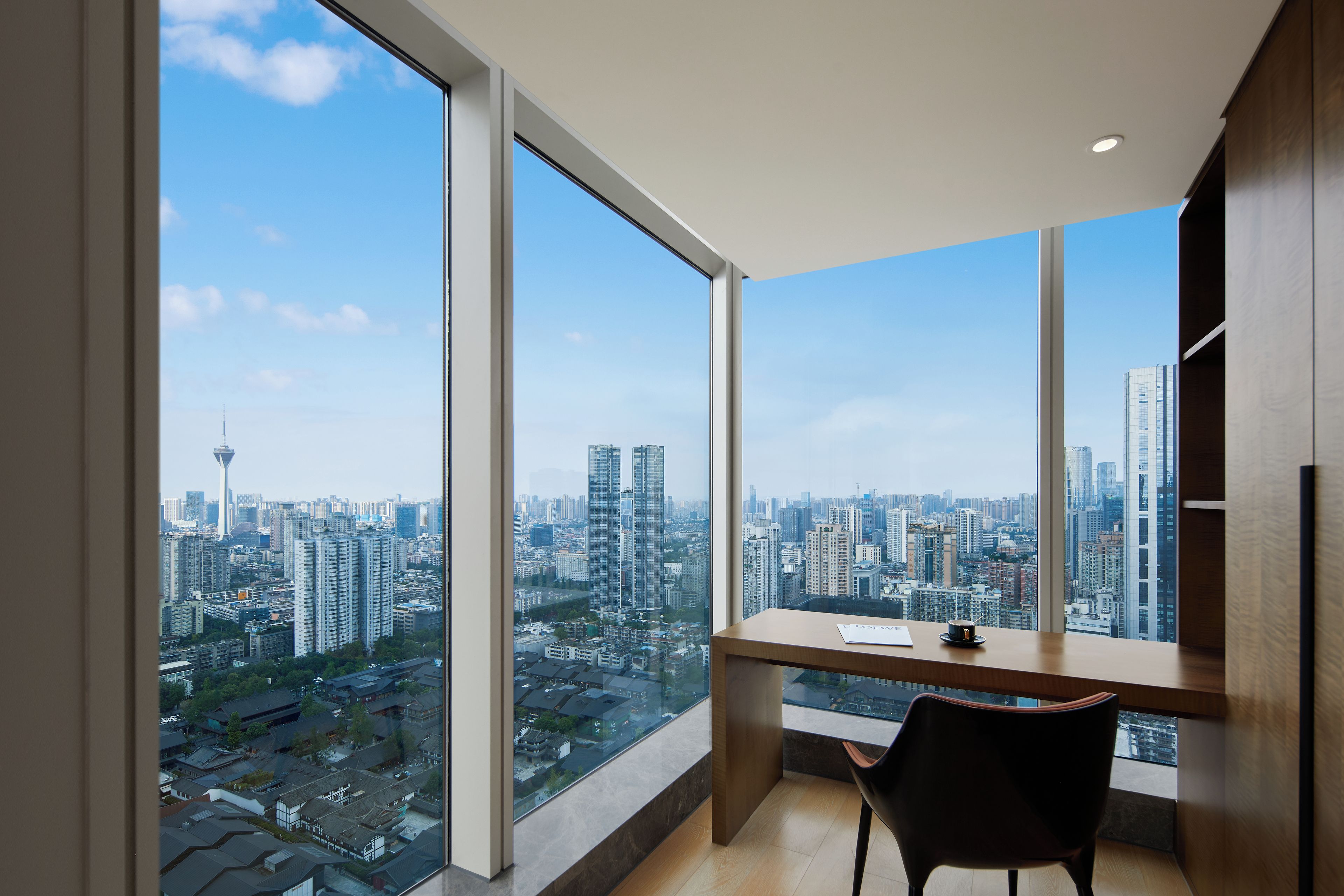 A modern room with large windows, a desk, and a chair.