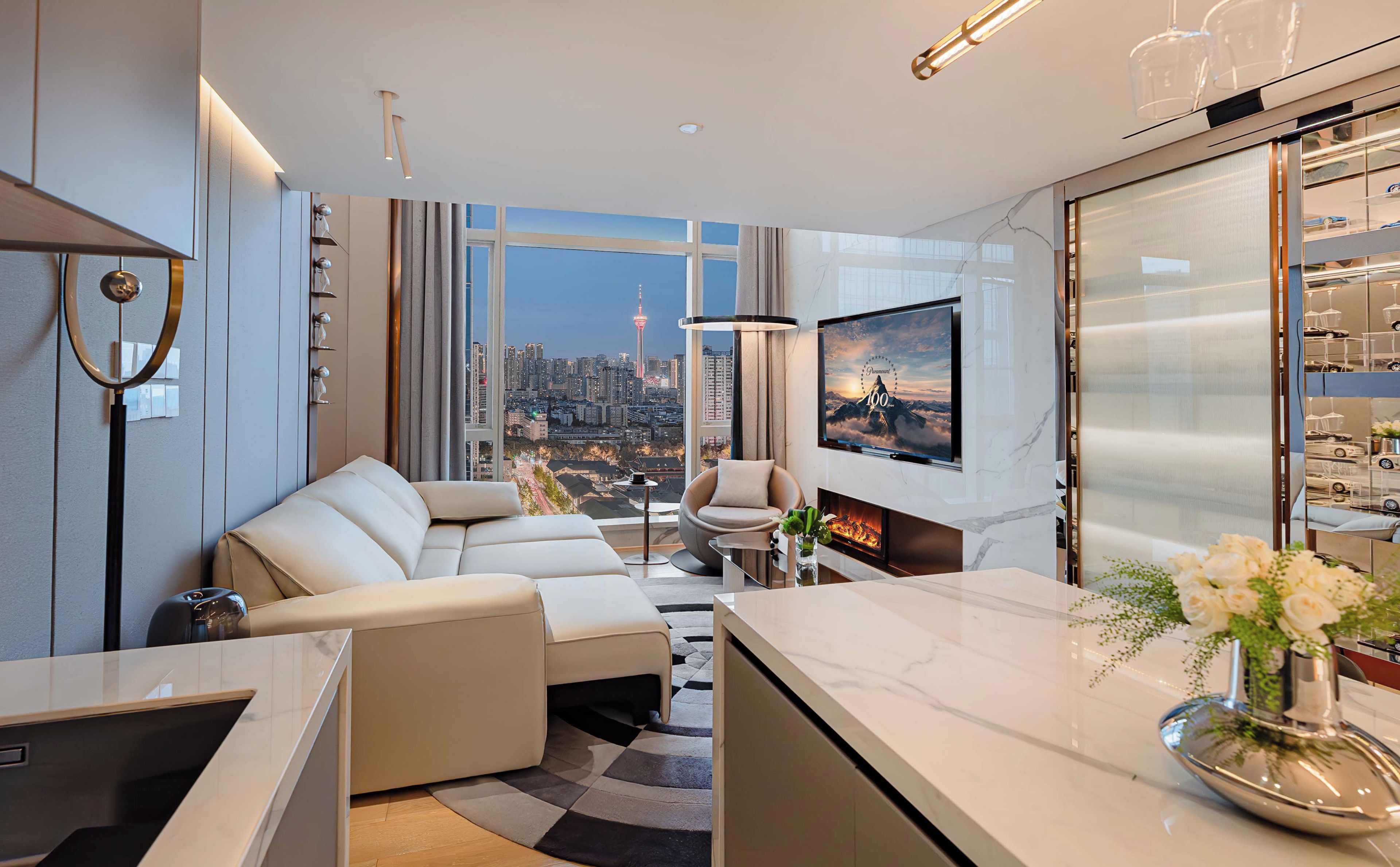 Ein modernes Wohnzimmer mit Stadtblick, einem Kamin und einem großen Fernseher.