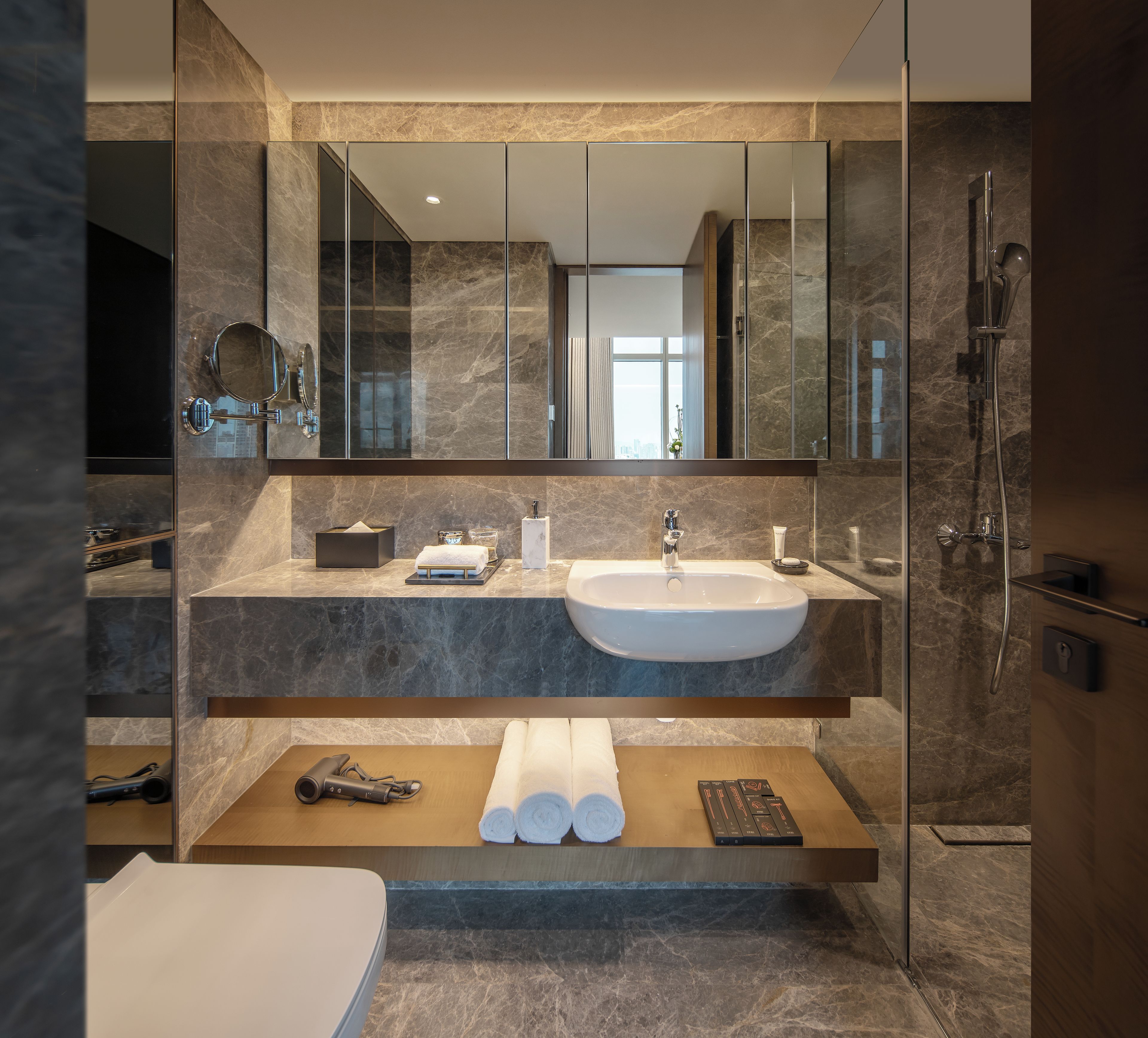 A modern bathroom with a large mirror, a sink, and a shower.