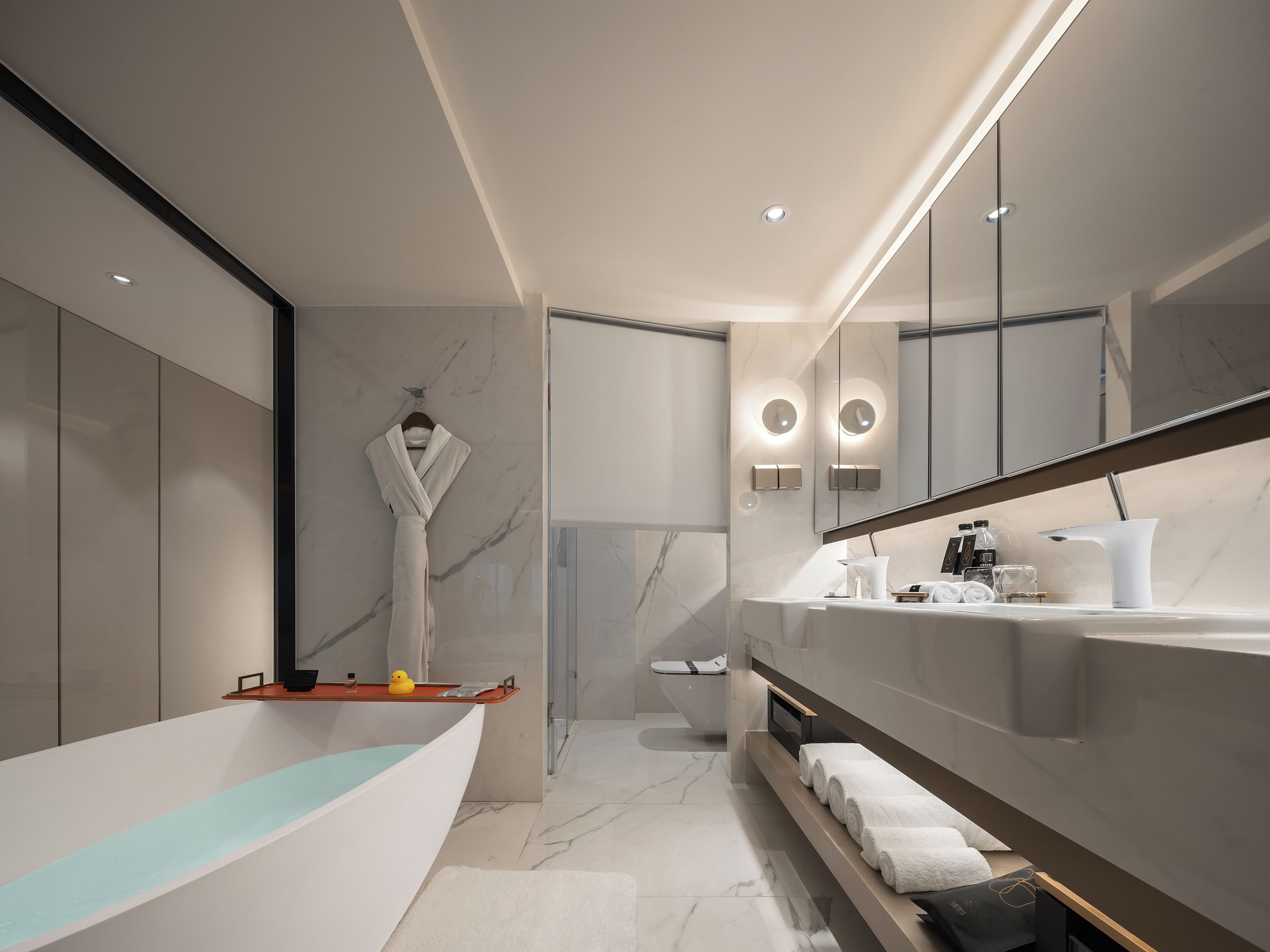 A modern bathroom with a freestanding bathtub, a vanity with a mirror, and a toilet.