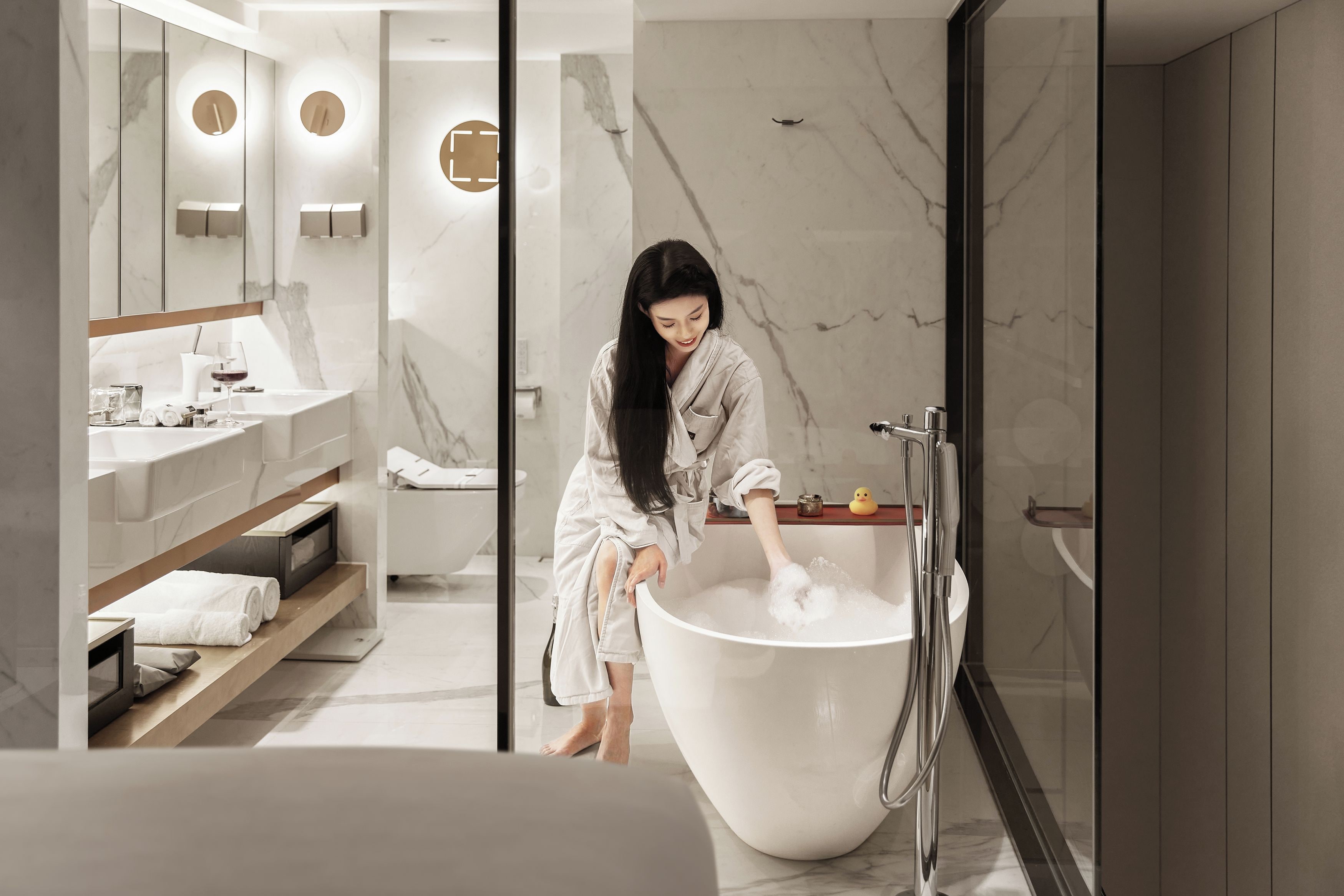 Une salle de bain moderne dotée d’une grande baignoire, d’une douche à parois de verre et d’un meuble-lavabo avec un miroir et des étagères.