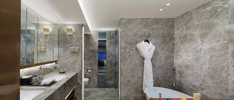 A modern bathroom with a marble wall, a large mirror, a bathtub, and a shower area.