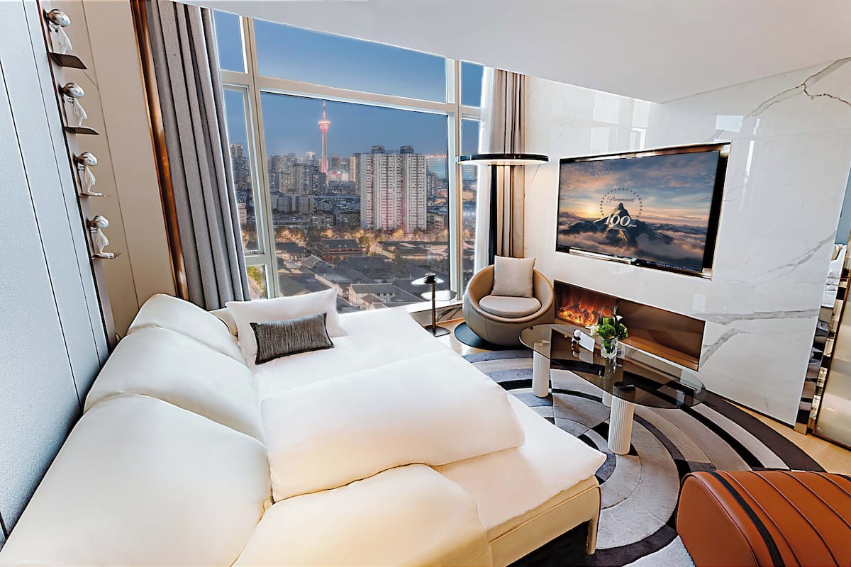 Una moderna camera d'albergo con un letto grande, una TV a parete, vista sulla città e un caminetto.