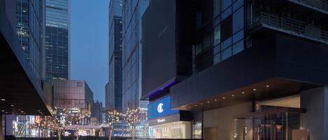 A modern hotel with a prominent 'C' logo, large glass windows, and a well-lit entrance.