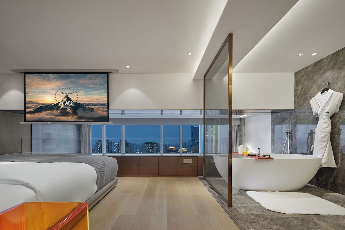 Una camera da letto moderna con un letto grande, una vasca da bagno e vista sulla città.