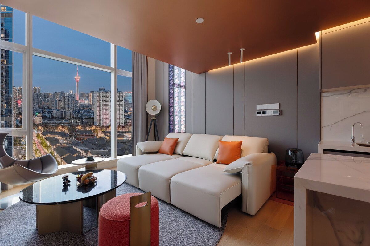 Una sala moderna con sofá, mesa de centro y vista a la ciudad.