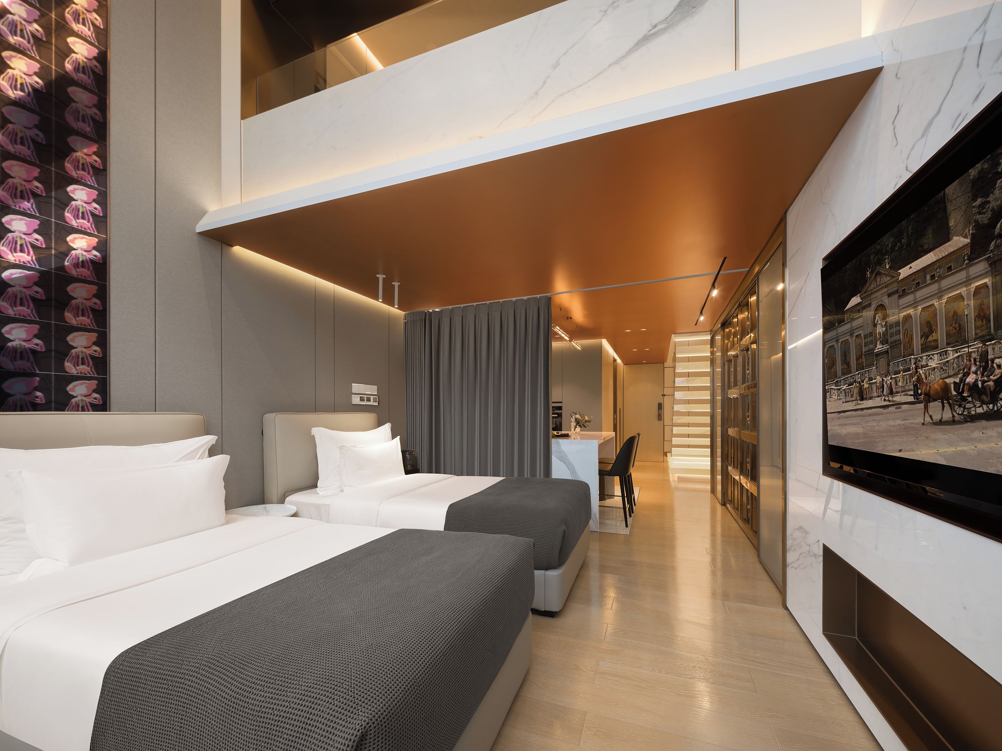 Une chambre d’hôtel moderne, dotée d’un grand lit, d’un bureau et d’un téléviseur diffusant des images d’un paysage urbain.