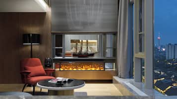 A modern living room with a red armchair, a round coffee table, a ship model, and a fireplace.