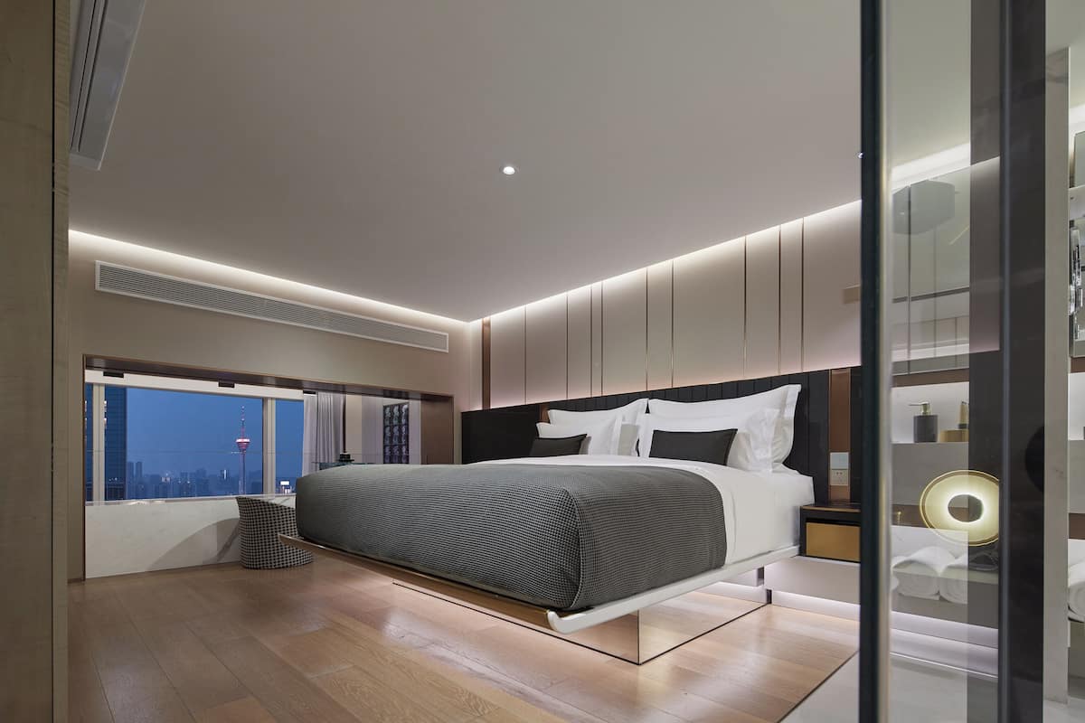 Una camera da letto moderna con un letto, vista sulla città e un'ampia finestra.