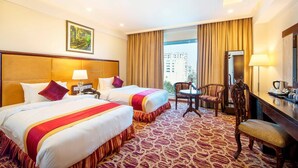 A hotel room with two beds, a desk, a chair, and a large window with curtains. - Ocean Pearl Resort Cox's Bazar (Cox's Bazar)