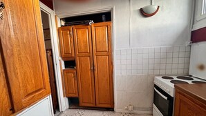 Une cuisine de taille réduite, dotée de meubles de rangement en bois, d’une cuisinière et de carreaux de sol à motifs.