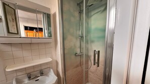 Une salle de bain avec une douche à parois de verre, un lavabo et un miroir au-dessus du lavabo.